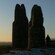 A sunset illuminates the view seen from a stone monument on a hillside